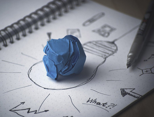Une boule de papier positionnée sur le dessin d'une ampoule qui représente l'idée